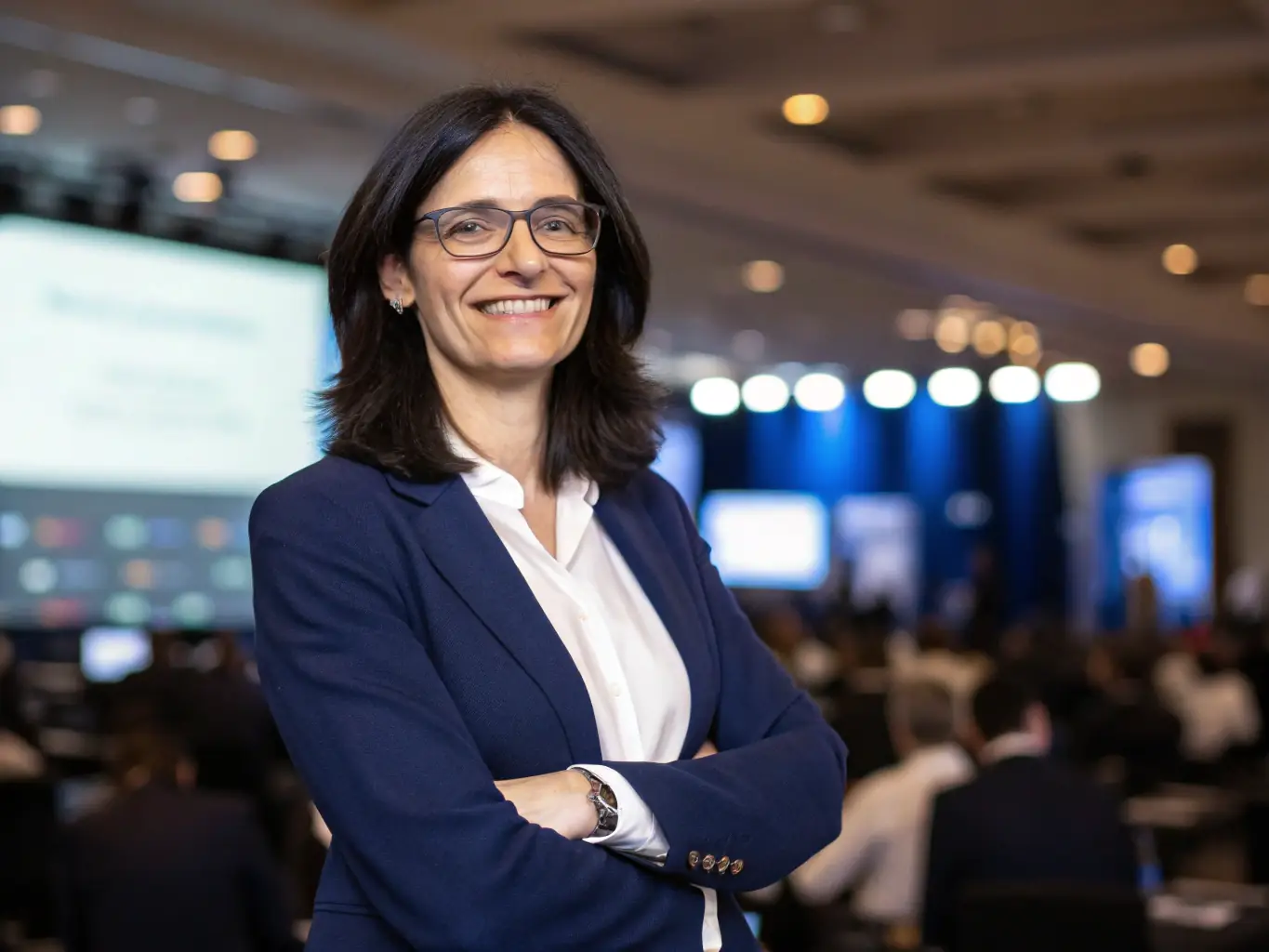 A professional headshot of a keynote speaker, Dr. Anya Sharma, a leading expert in AI and machine learning, smiling confidently against a blurred background of a tech conference.